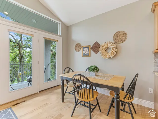 Vaulted ceiling with an upper transom window, double patio doors, and wood-finish flooring