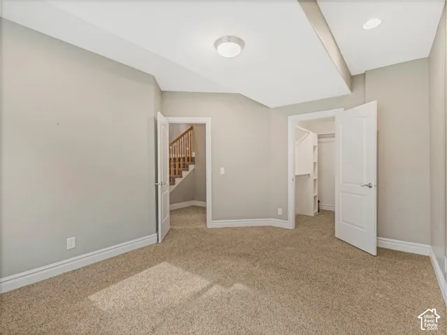 Neutral tone wall paint, carpeted flooring, built-in closet shelving, staircase with wood balusters, and overhead lighting fixtures