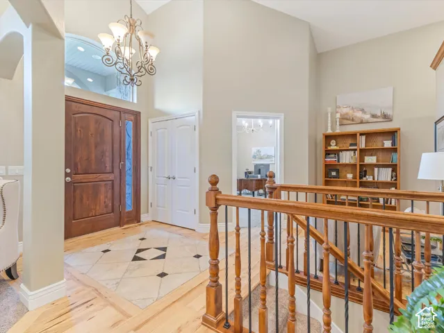 Two-story foyer with a custom wooden front entry door, decorative transom window, and chandelier
