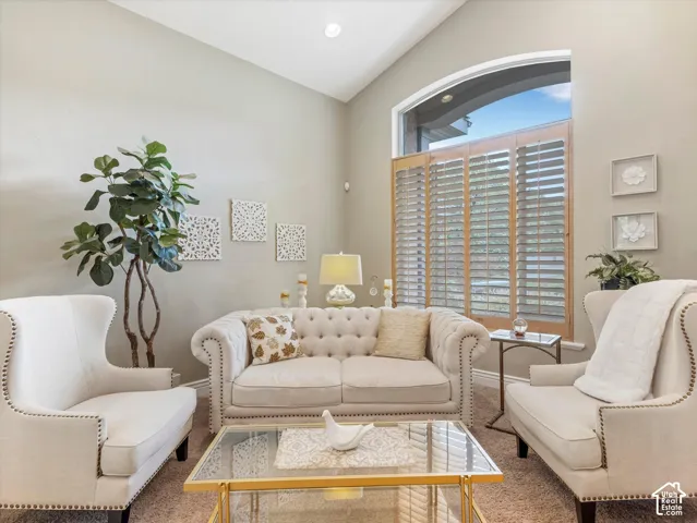 Vaulted ceiling, arched window with plantation shutters, recessed lighting, and wall-mounted art