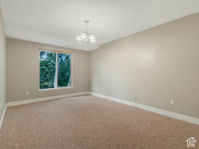 Carpeted room with a large window, neutral wall paint, white trim, and a ceiling-mounted light fixture