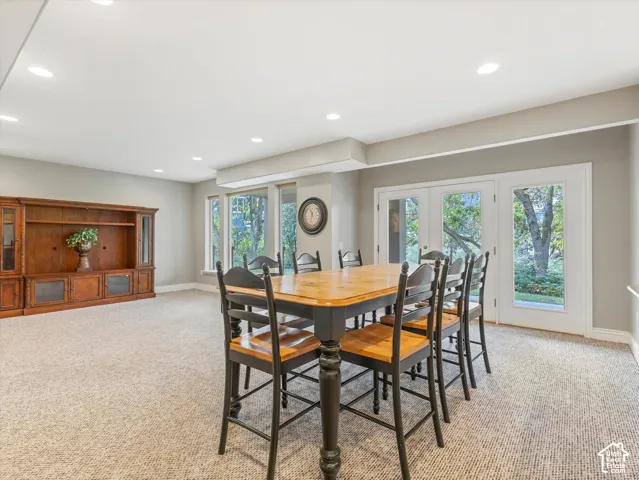 Recessed lighting, French doors, multiple windows, and light-toned carpeting create a bright and inviting atmosphere