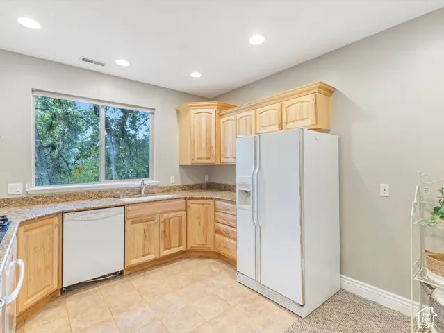 Kitchen with natural wood cabinetry, light-toned countertop, and tile flooring