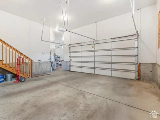Concrete flooring with a white paneled garage door and an automatic opener