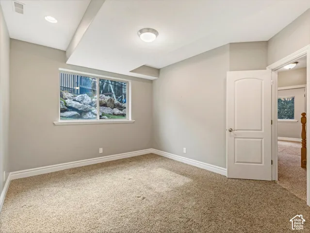 Recessed lighting, neutral wall paint, white trim, carpeted flooring, and a window with a rock landscaping backdrop