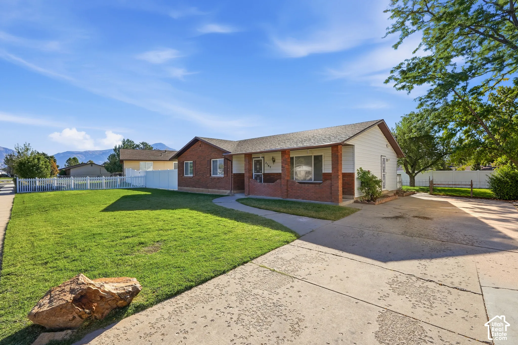 Brick and siding exterior with a concrete driveway, a concrete walkway, and a manicured lawn