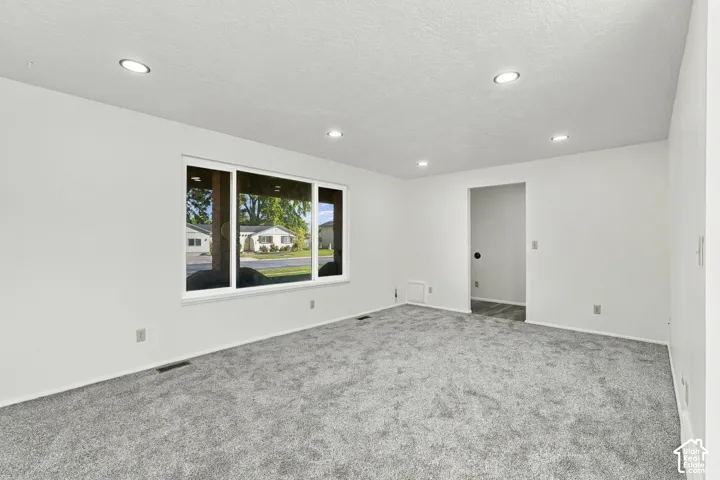 Carpet flooring, white painted walls, recessed lighting, and a large window