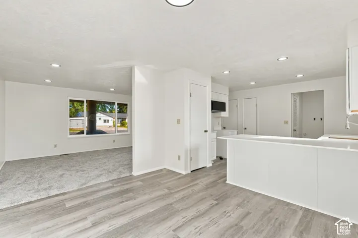 Open-concept living space with wood-finish flooring, recessed lighting, and a white breakfast bar