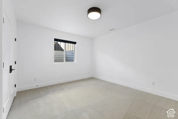 Neutral-toned carpeting, white walls, and a single window with a privacy blind