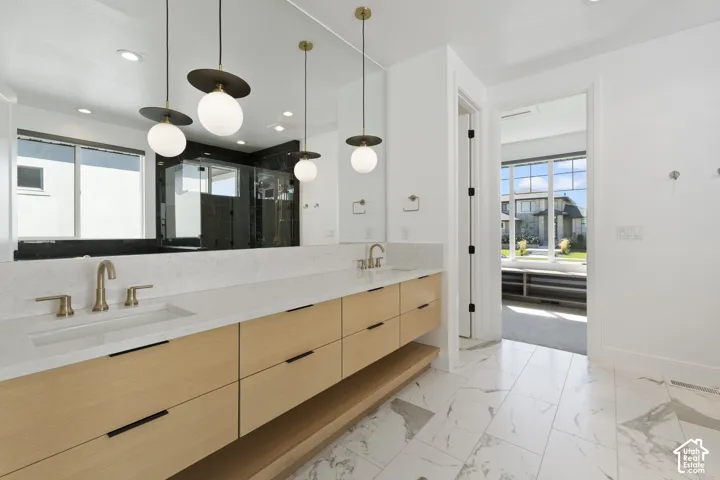 Dual vanity with light wood-finish cabinetry, white countertop, and brass fixtures