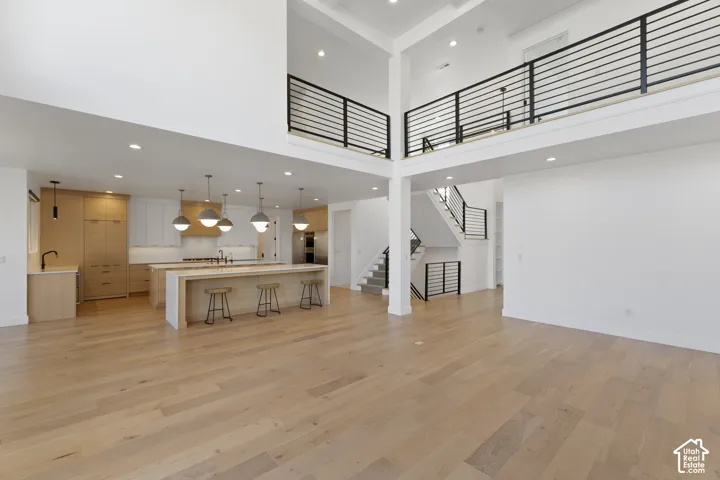 Open-concept living space featuring wood-finish flooring, a two-story ceiling, and a kitchen with an island and pendant lighting