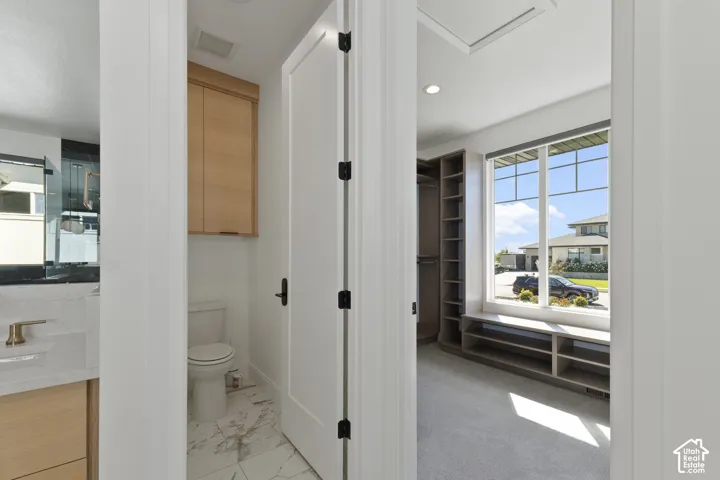 Walk-in closet with built-in shelving, large window, and integrated window bench