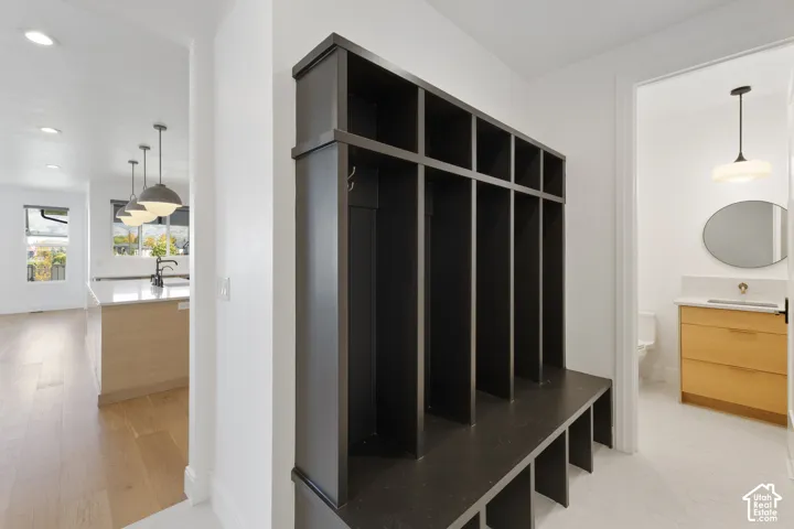 Built-in cabinetry with bench seating, wood-finish flooring, recessed lighting, pendant lighting, and a floating vanity with a vessel sink