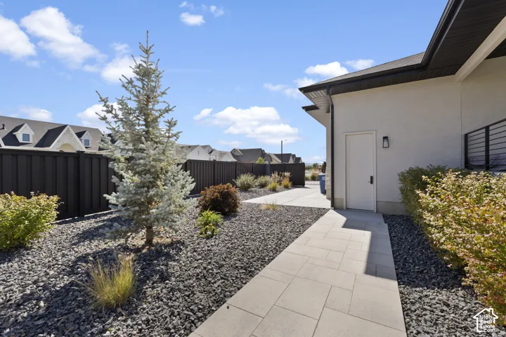 Hardscaped side yard featuring a tiled pathway, dark gravel, and an evergreen tree