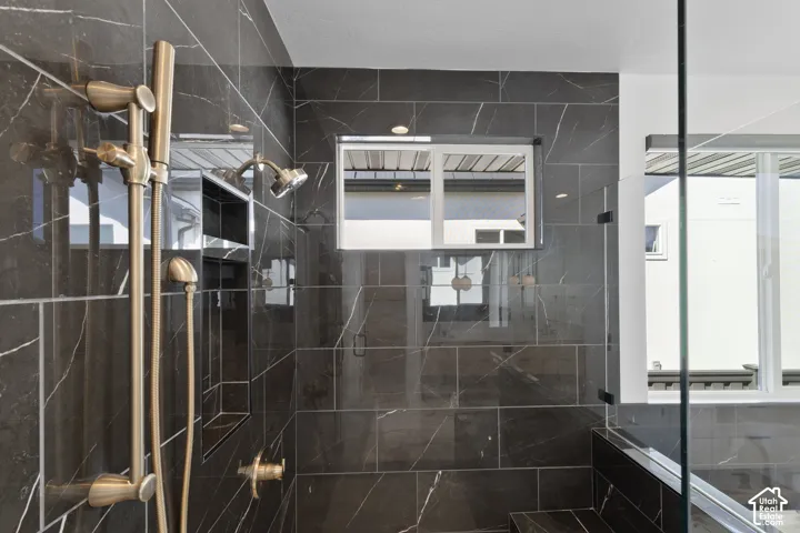 Shower with dark tile walls, an integrated niche, a built-in bench, and brass fixtures