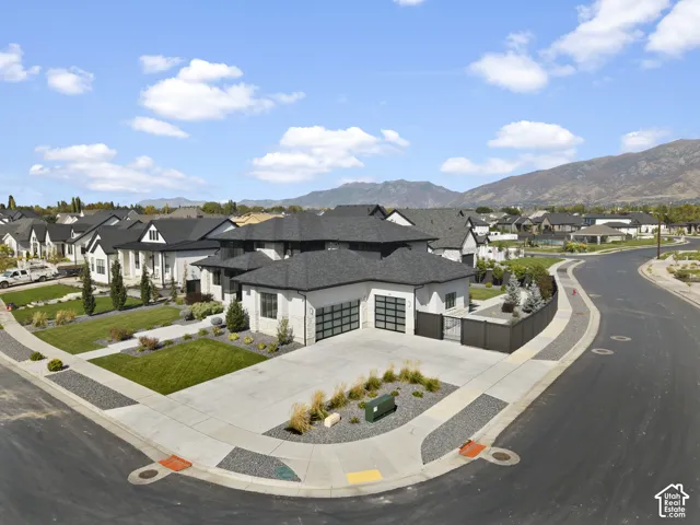 Modern exterior featuring a light-toned facade, dark-toned roof, and a multi-car garage with frosted glass doors