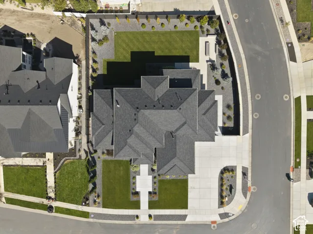 Expansive property featuring a multi-gabled roofline, concrete driveway, front lawn, and a backyard with a manicured lawn and mature landscaping