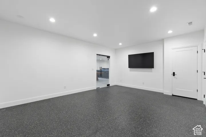 Recessed lighting, dark speckled flooring, solid core door with matte black hardware, and a glass-paneled entry