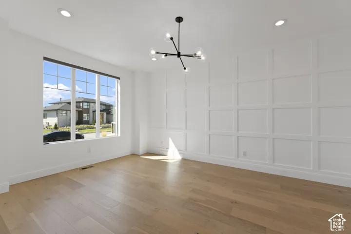 Wood-finish flooring, recessed ceiling lighting, a contemporary chandelier, a large multi-pane window, and decorative wall paneling
