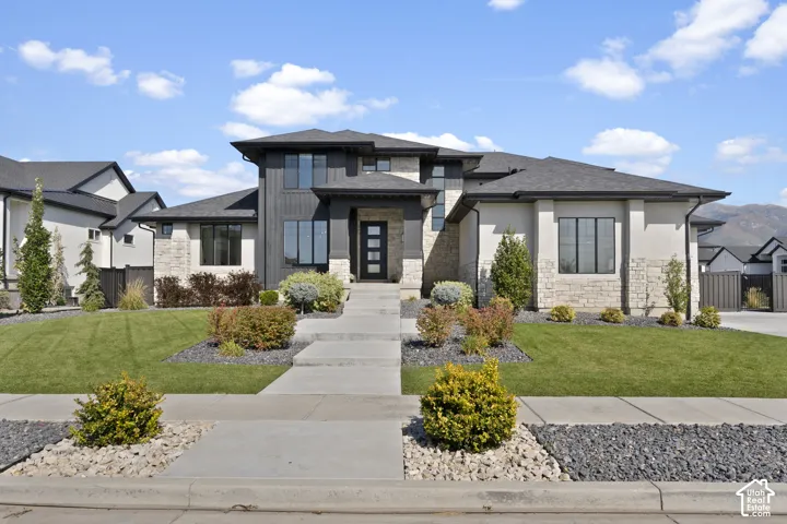 Contemporary exterior with mixed material facade, clean-lined landscaping, concrete pathway, and a prominent front entry