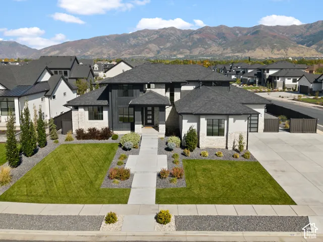 Contemporary architecture with dark trim accents, light stone facade, and a dark shingle roof