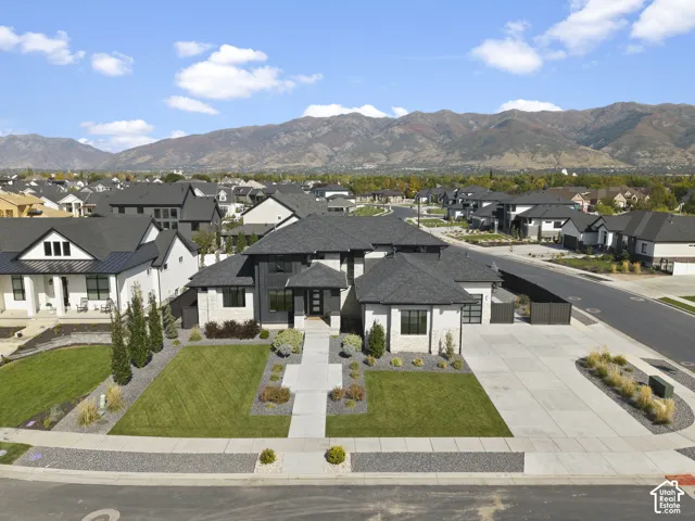Modern home featuring a striking black and charcoal exterior with contemporary architectural lines, anchored by a professionally landscaped front yard with manicured lawn, geometric hardscape borders, and specimen plantings