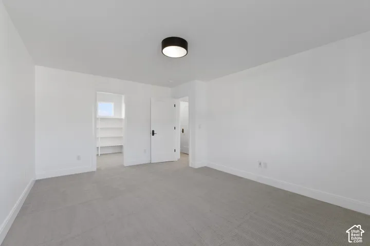 Neutral wall paint, light-toned carpet flooring, a built-in closet with shelving, modern ceiling light fixture, and white interior doors