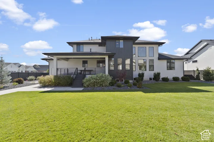 Contemporary exterior with multi-story windows, a covered patio, and an expansive lawn