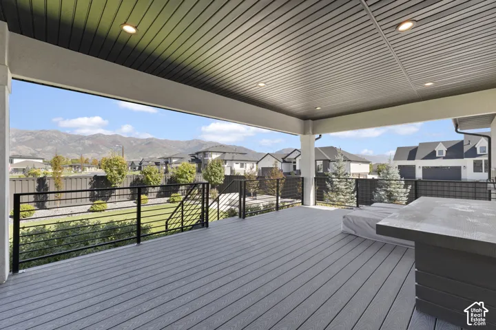 Expansive covered deck featuring composite decking, recessed lighting, and black metal railings