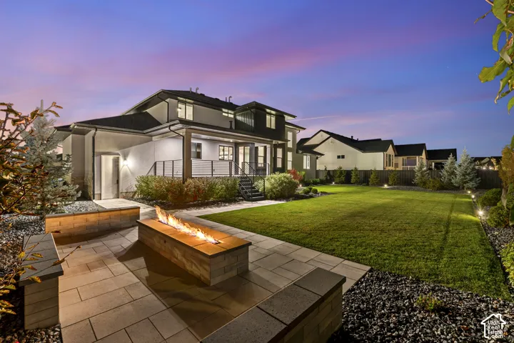 Expansive backyard featuring a manicured lawn, established landscaping, and perimeter lighting