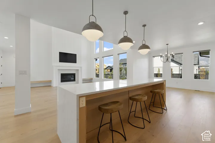 Island with solid surface countertop, wood-finish flooring, white fireplace, and multiple windows