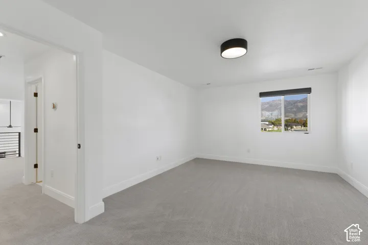 Recessed lighting and a modern flush-mount ceiling fixture illuminate this carpeted room