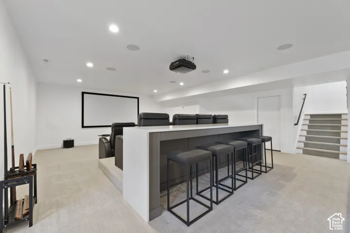 Entertainment area featuring a large projection screen, built-in bar with countertop, recessed lighting, and carpet flooring