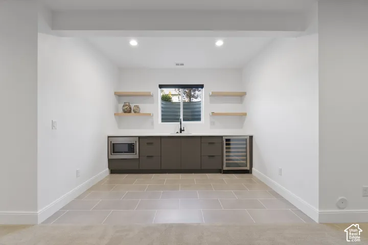 Built-in wet bar with a microwave, beverage refrigerator, and open shelving