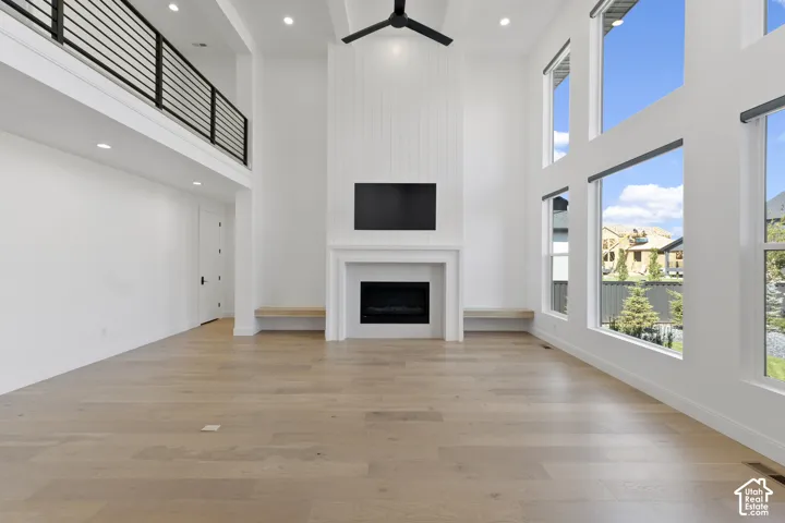 Vaulted ceilings, wood-finish flooring, a contemporary fireplace, and a second-story open rail balcony