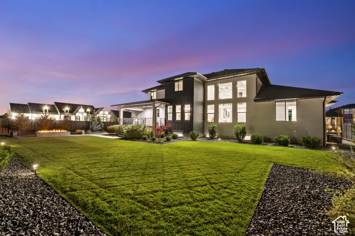 Expansive rear yard with manicured lawn, a concrete fire pit, and decorative rock landscaping