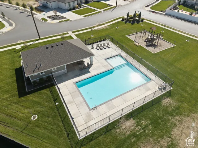 Community swimming pool with a concrete deck, adjacent covered patio, and nearby playground