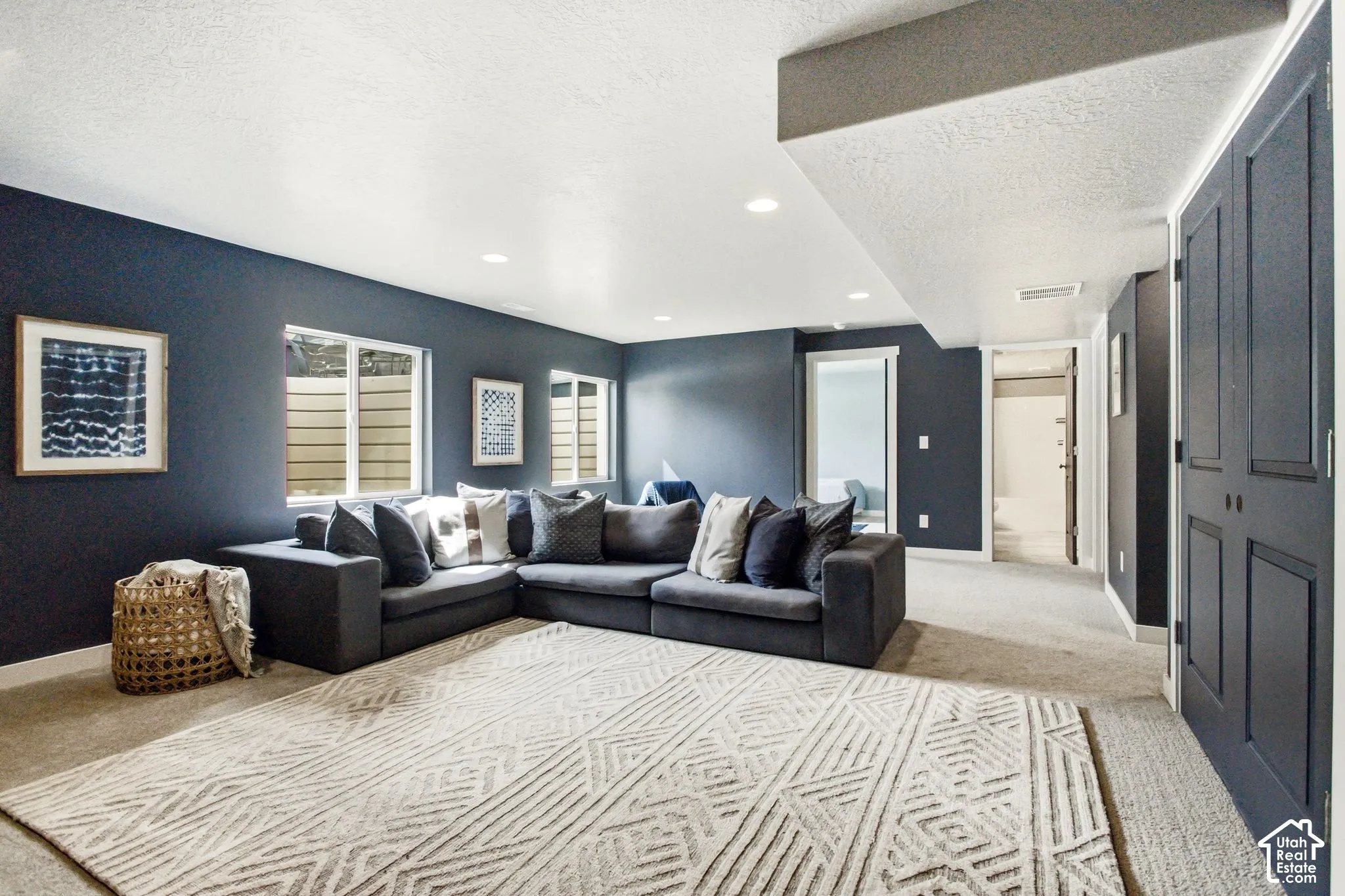 Recessed lighting illuminates the space, featuring dark-painted walls, white trim, and light-colored carpeting