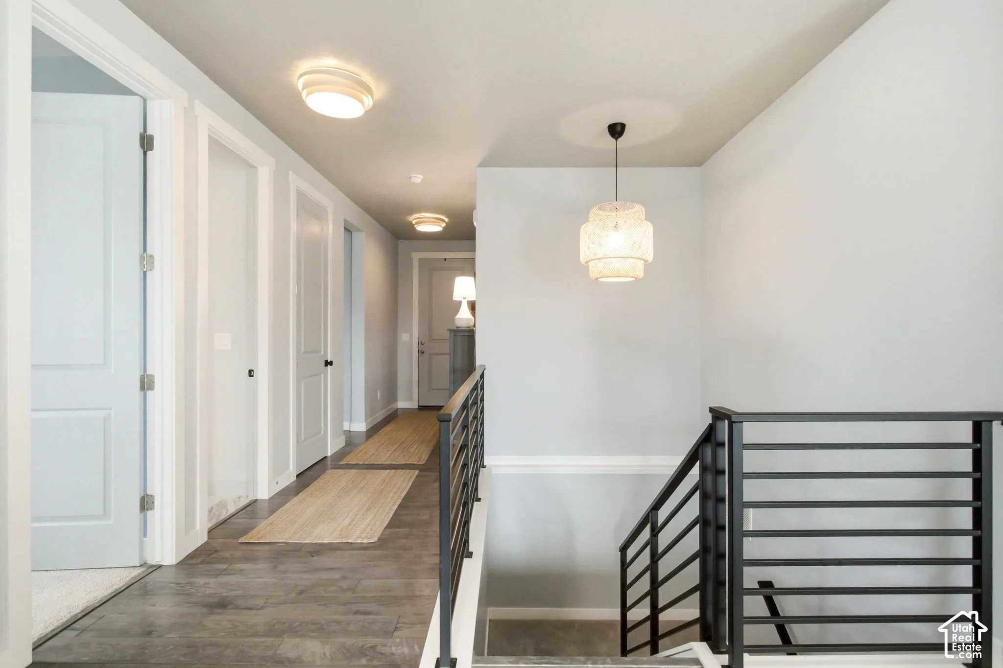 Wood-finish flooring with a modern staircase featuring black metal railings