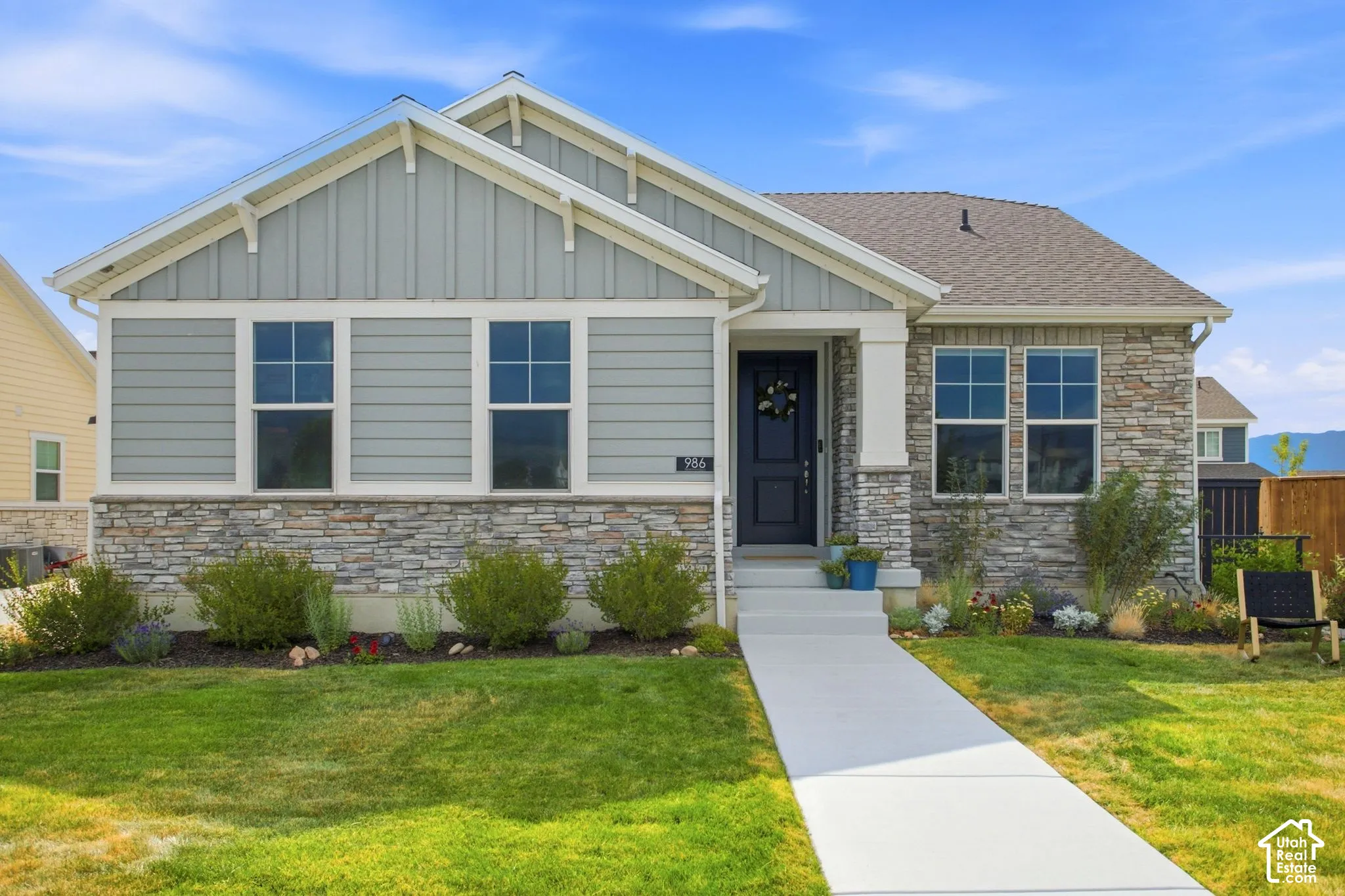 Modern ranch-style home featuring a mixed-material exterior with horizontal fiber cement siding and stone veneer base