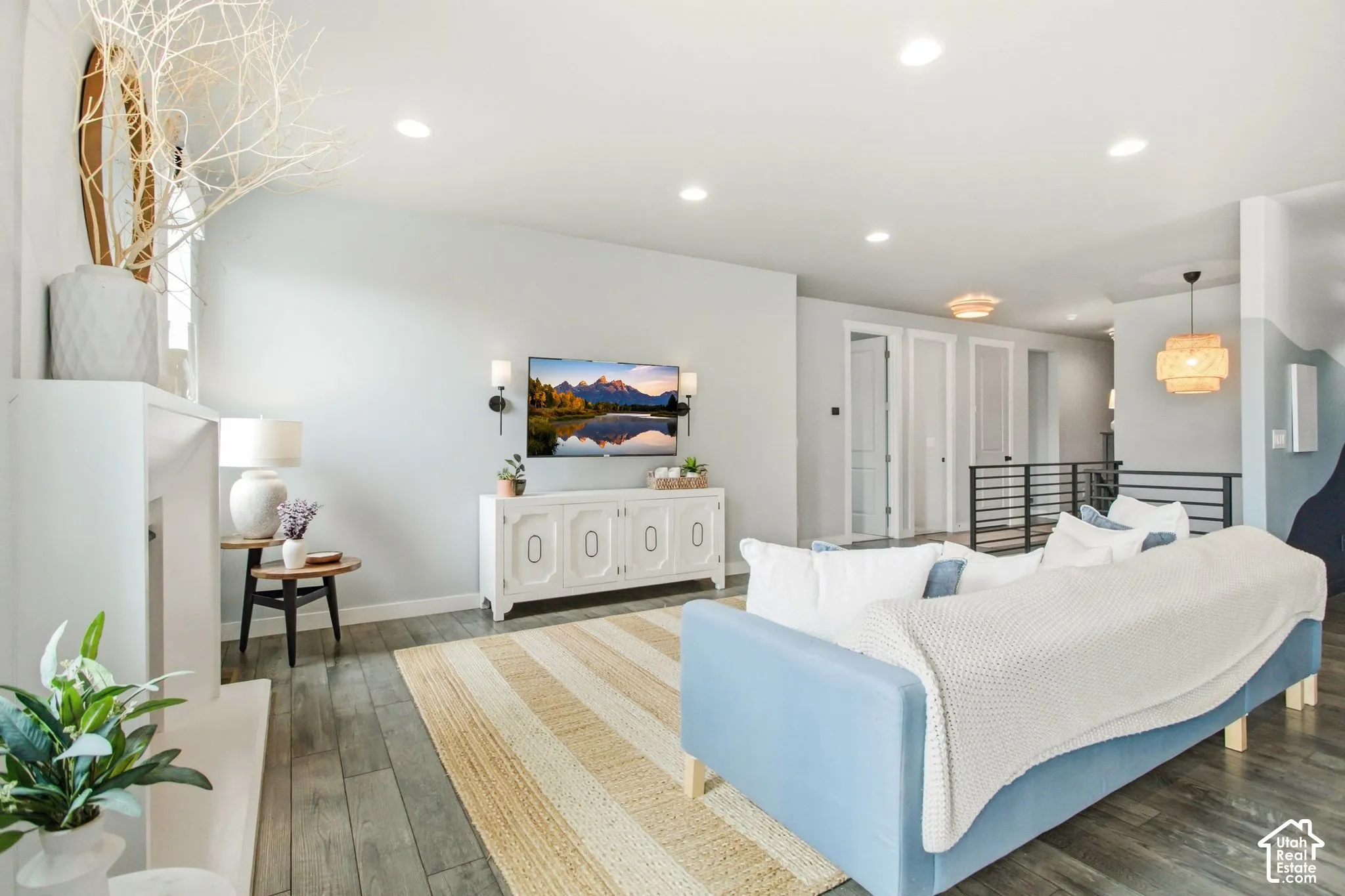 Recessed ceiling lighting, wood-finish flooring, white fireplace surround, and multiple interior doors with modern hardware