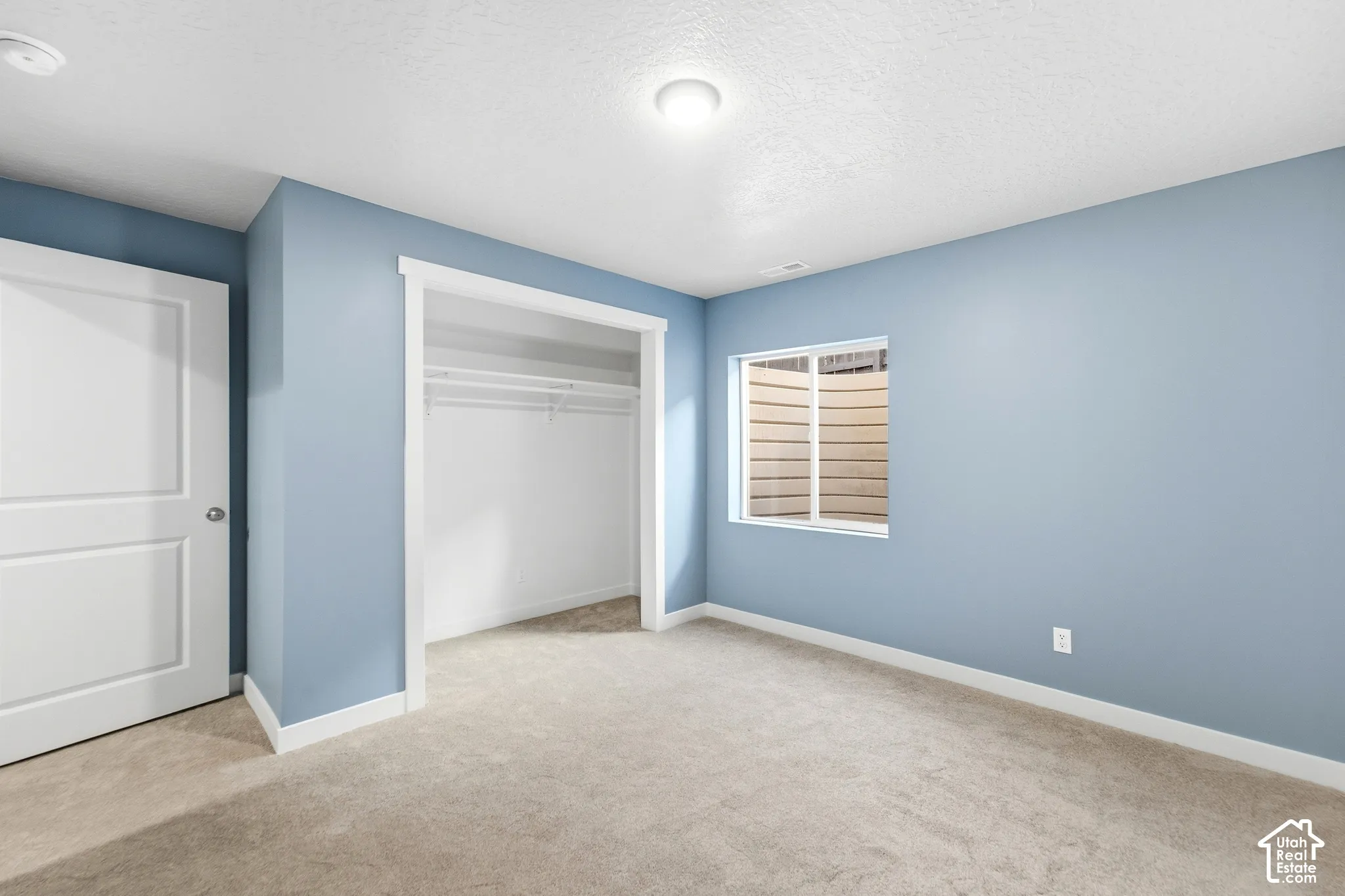 Recessed window with white trim, wall-to-wall carpeting, and a built-in closet with shelving