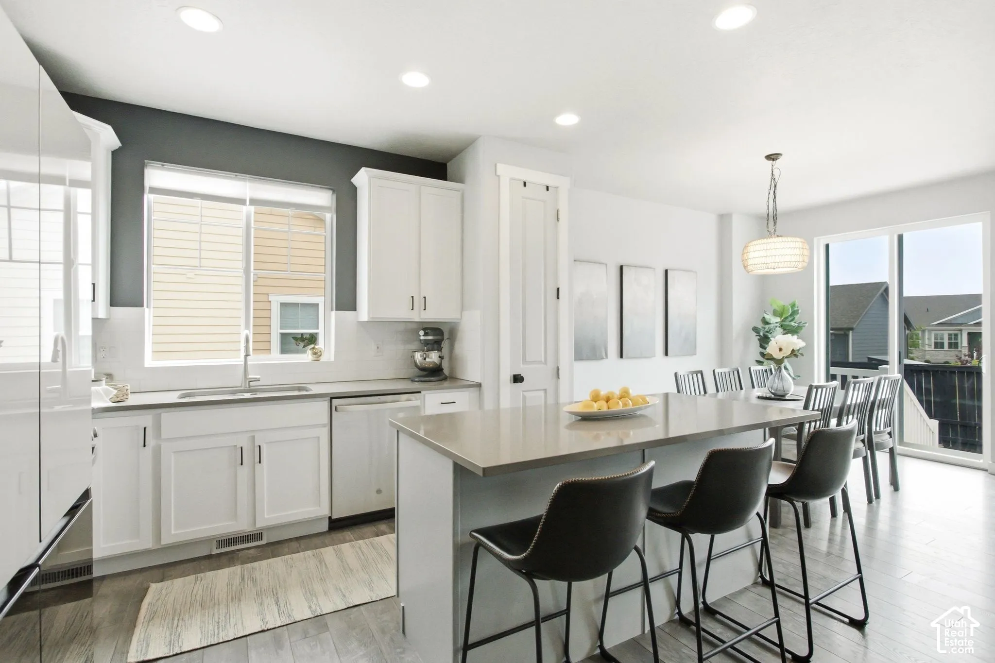 Open-concept kitchen with recessed lighting, light wood-finish flooring, a kitchen island with seating, white cabinetry, and sliding glass patio doors