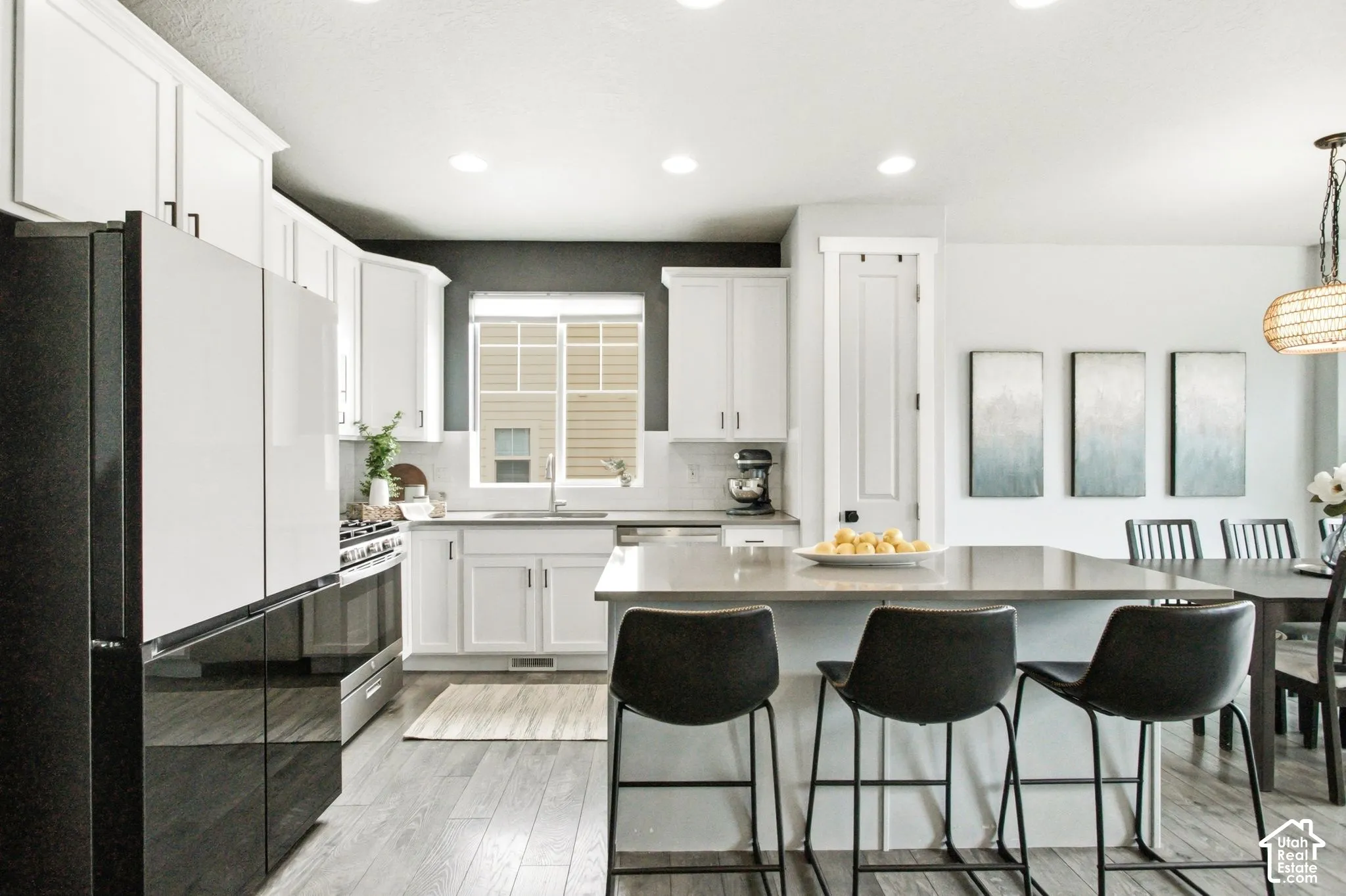 Kitchen featuring white cabinetry, wood-finish flooring, a central island with countertop seating, stainless steel appliances, and recessed lighting