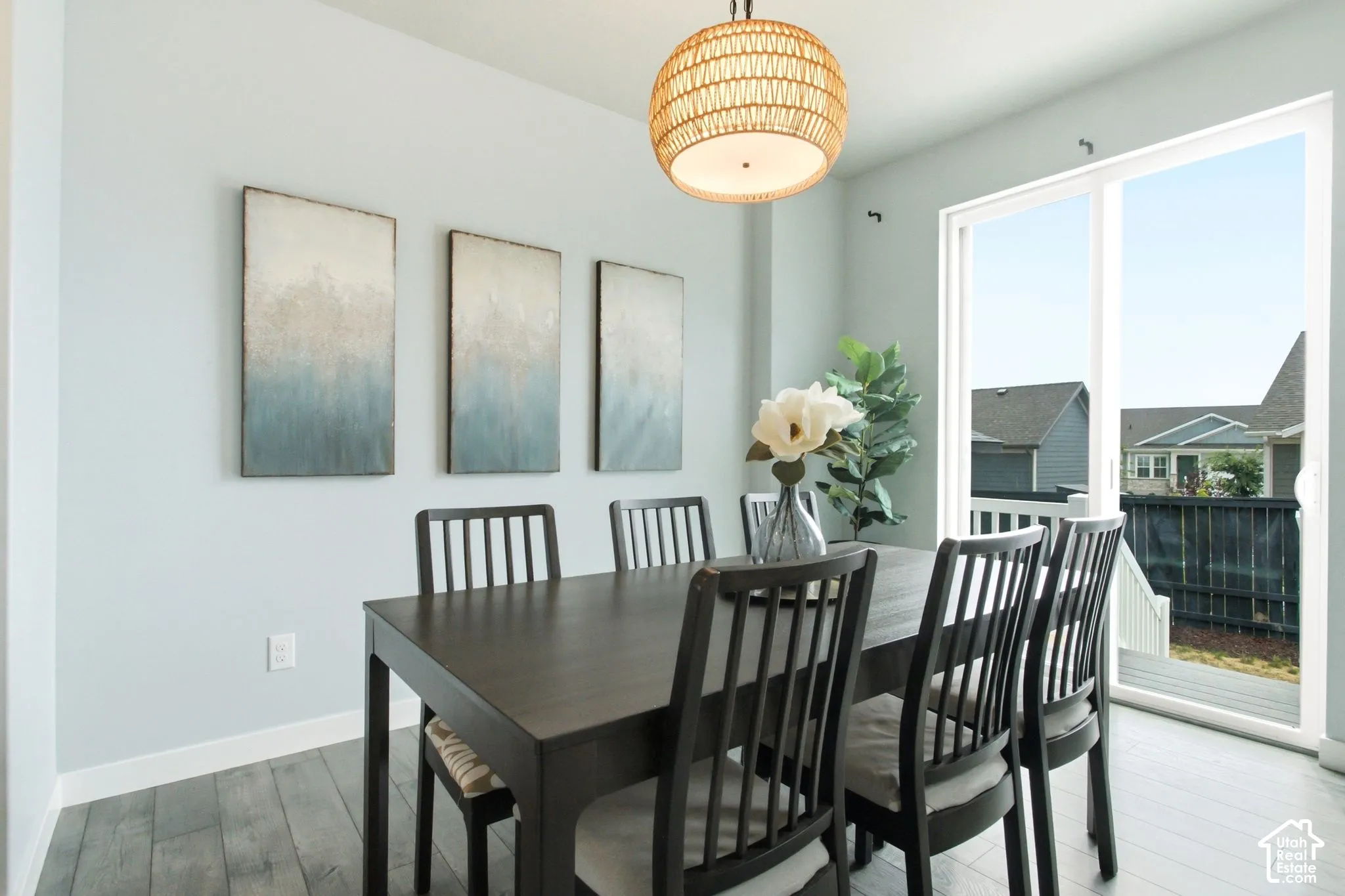 Wood-finish flooring, a woven pendant light fixture, and a sliding glass door providing outdoor access