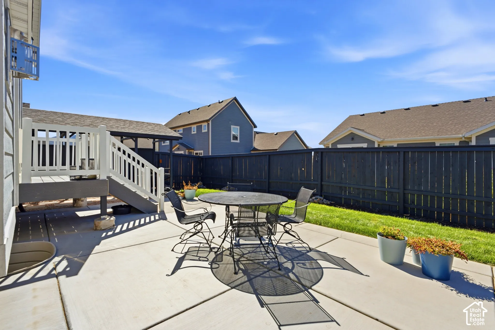 Concrete patio area featuring a white railing deck and a dark stained privacy fence