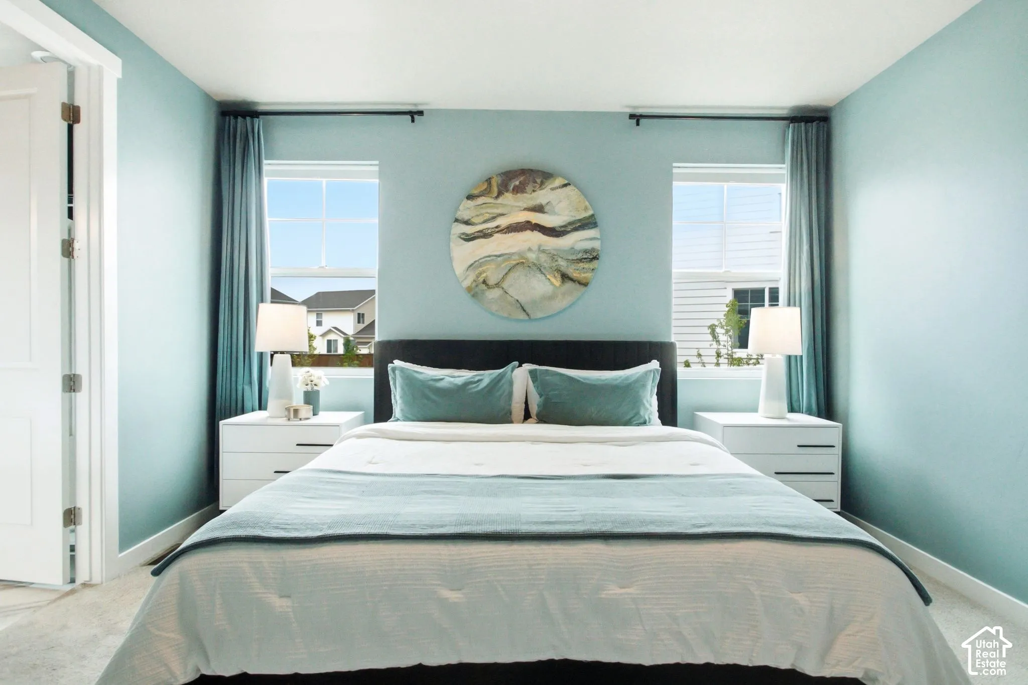 Light blue walls with white trim, two windows with blinds, and white paneled door
