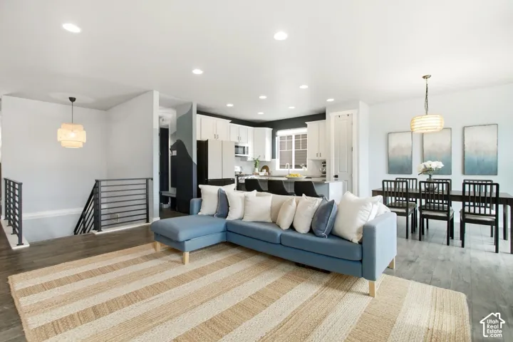 Open-concept living area with wood-finish flooring, recessed lighting, and a modern horizontal metal railing system
