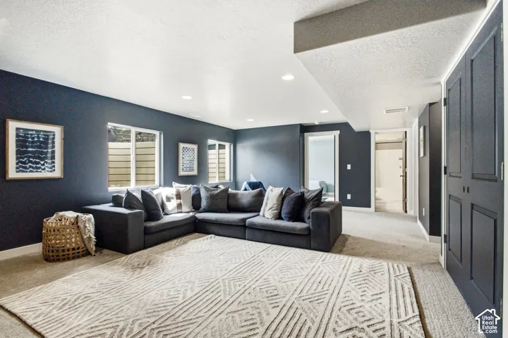 Recessed lighting illuminates the space, featuring dark-painted walls, white trim, and light-colored carpeting
