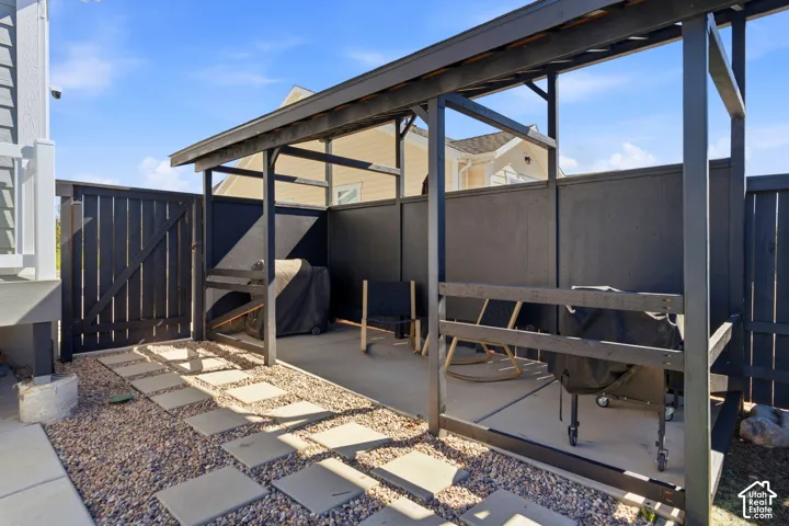 Outdoor patio area featuring a pergola, privacy fencing, a concrete pad, and a gravel path with stepping stones